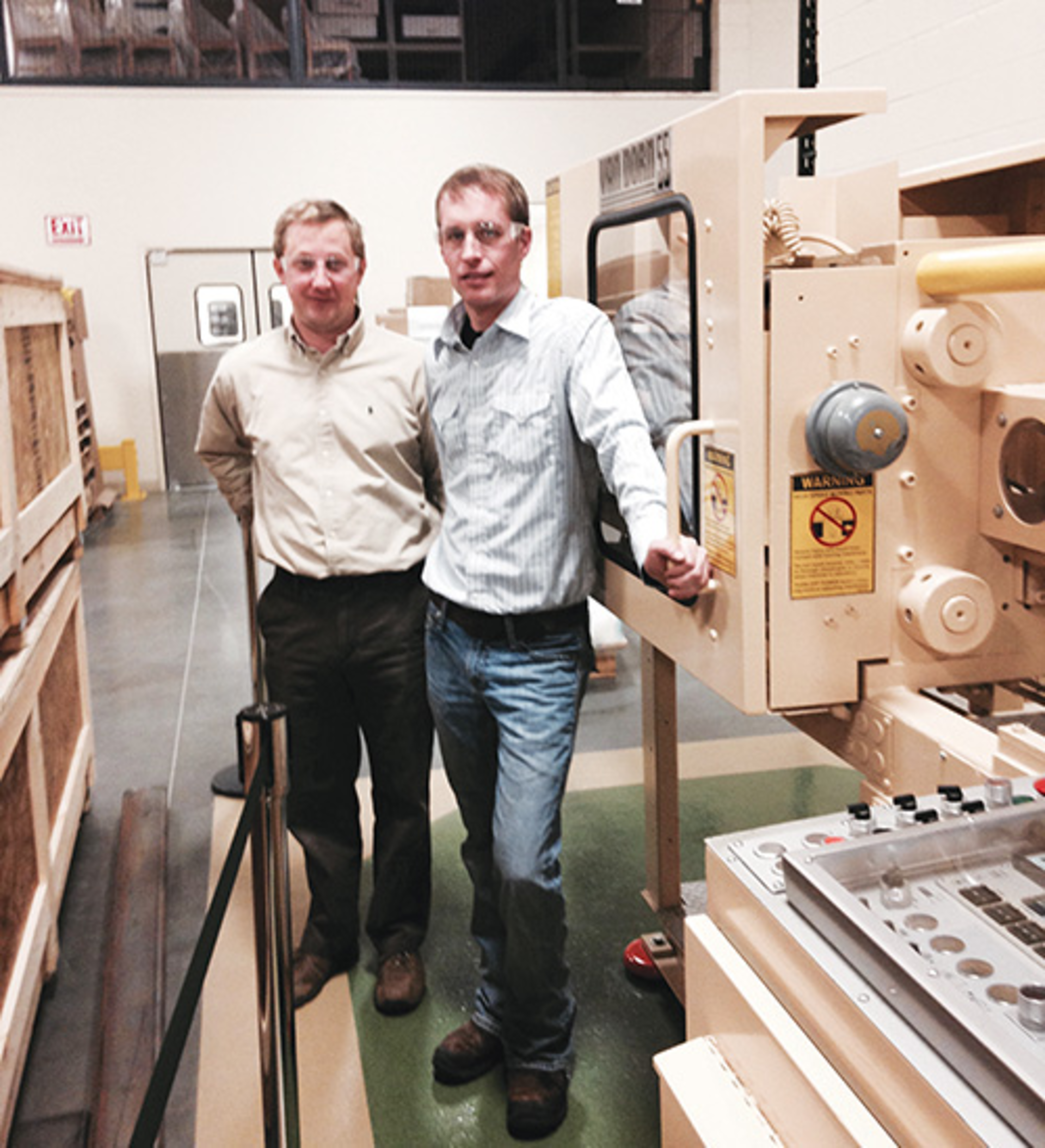 Rob Cooney, left, and Ryan Katen stand next to the press that started it all for Plastikos &acirc;&euro;&rdquo; a 55-ton Van Dorn.