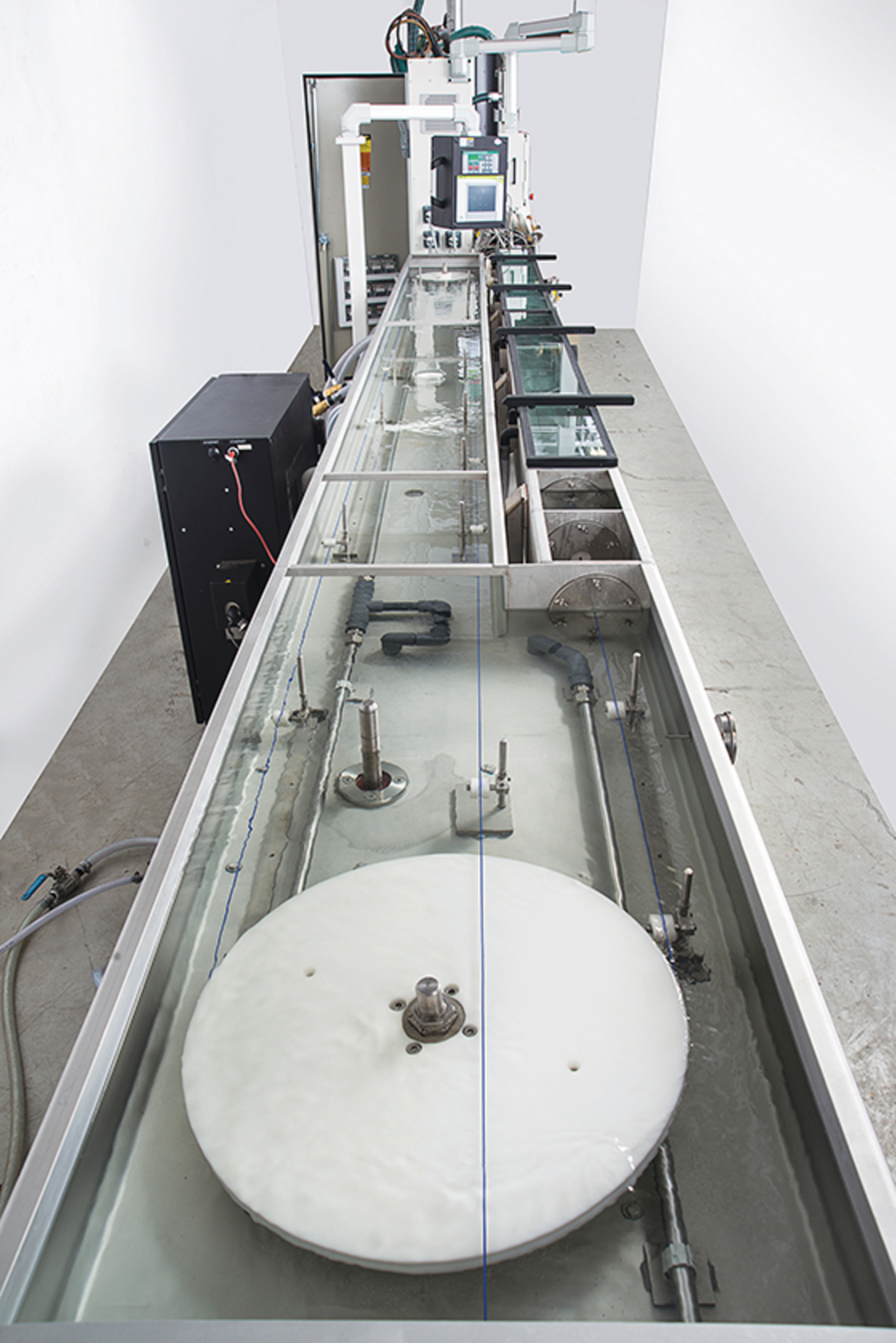 Extruded filament passes through a Conair HTMP multi-pass cooling and sizing tank.