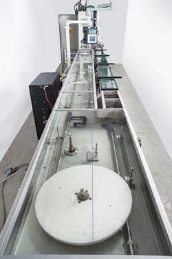 Extruded filament passes through a Conair HTMP multi-pass cooling and sizing tank. Extruded filament passes through a Conair HTMP multi-pass cooling and sizing tank.