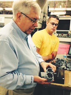 Ken Parker holds a part for a commercial dishwasher that was milled to add a groove and thread. Technician Adam Rice looks on. Ken Parker holds a part for a commercial dishwasher that was milled to add a groove and thread. Technician Adam Rice looks on.