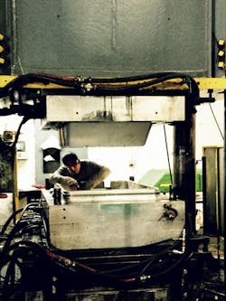 A worker inspects a compression mold at CTC. A worker inspects a compression mold at CTC.