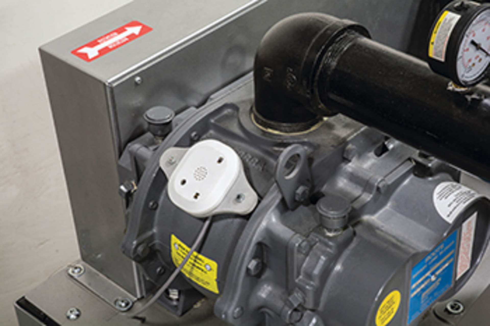 A white Prophecy sensor is mounted on a vacuum pump that is used for conveying plastic pellets.