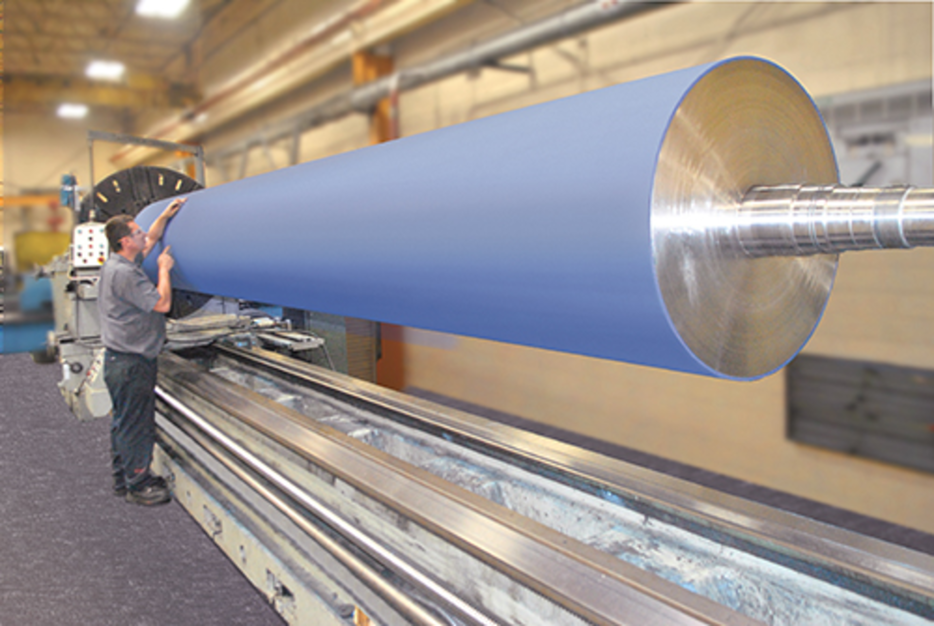 A technician inspects a large rubber roller made by Menges Roller.