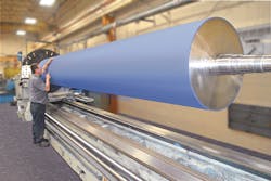 A technician inspects a large rubber roller made by Menges Roller. A technician inspects a large rubber roller made by Menges Roller.