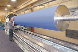 A technician inspects a large rubber roller made by Menges Roller. A technician inspects a large rubber roller made by Menges Roller.