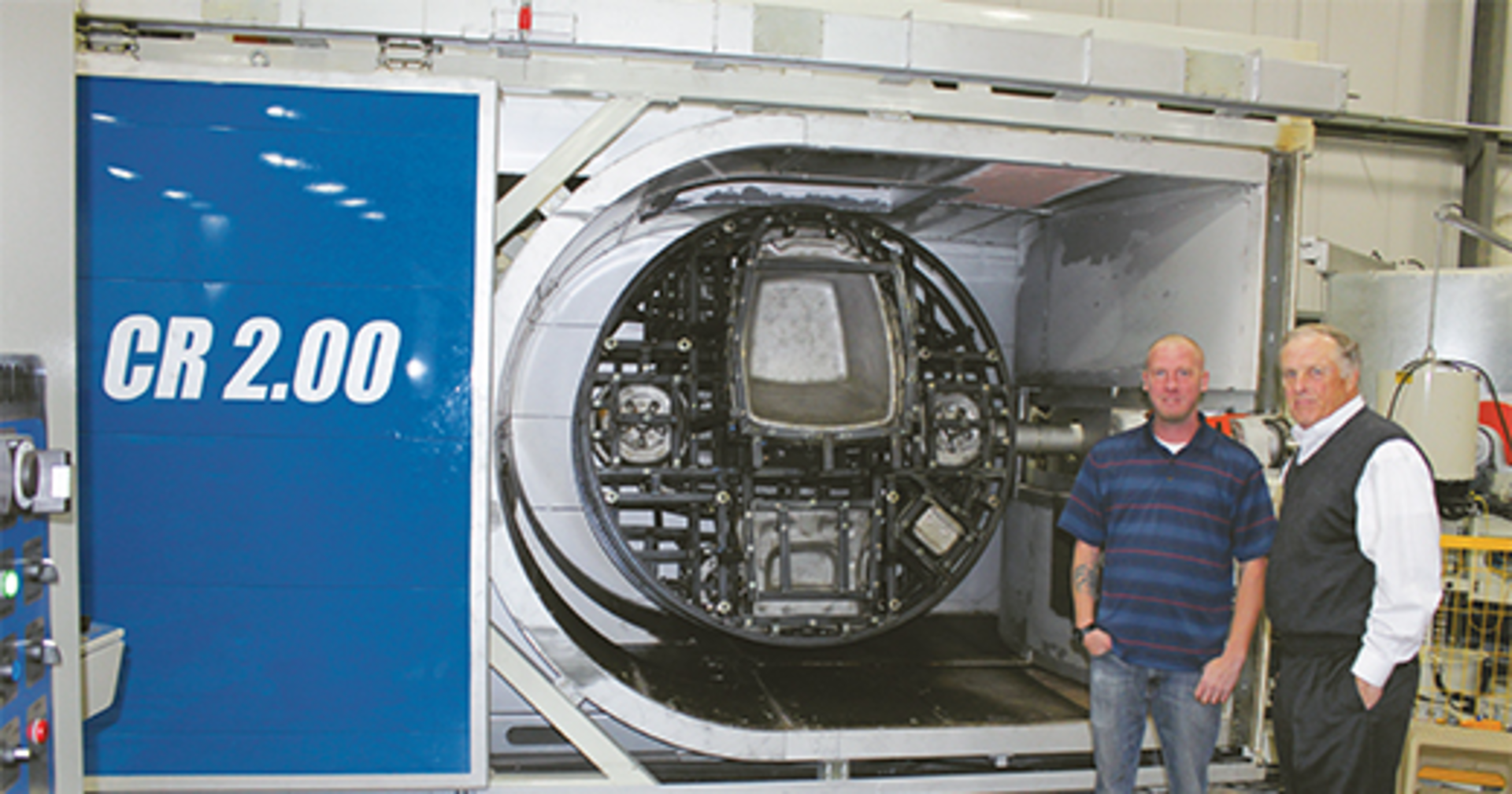 Simplay3 founder Tom Murdough, right, and plant manager Gabe Parsons stand beside a Rotoline rotomolding machine.