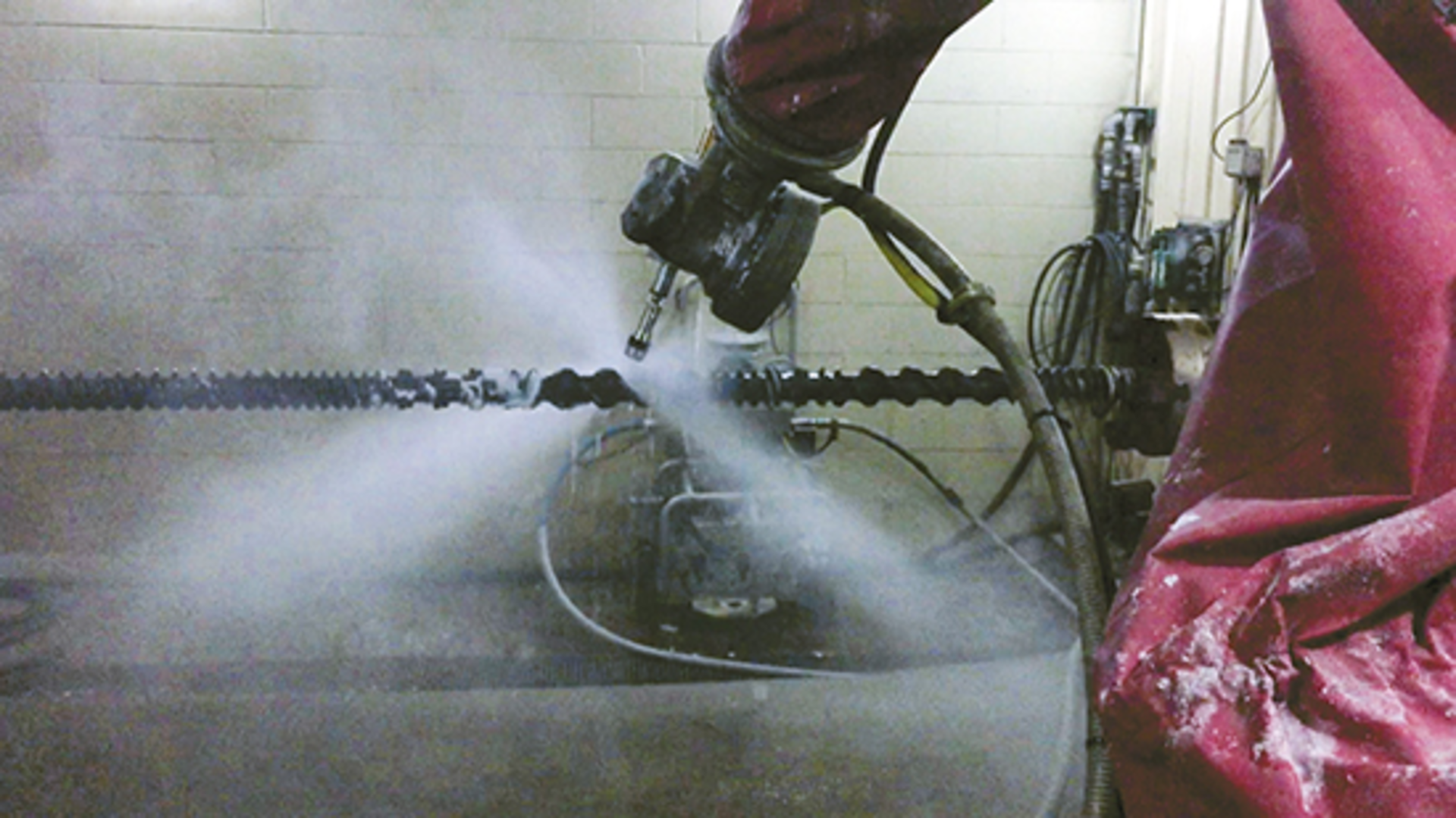 A robot cleans a screw using a high-pressure water jet.