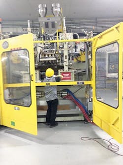 Quality assurance: An employee conducts routine maintenance on a blow molding machine.