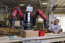 An employee works alongside a Baxter cobot from Rethink Robotics.