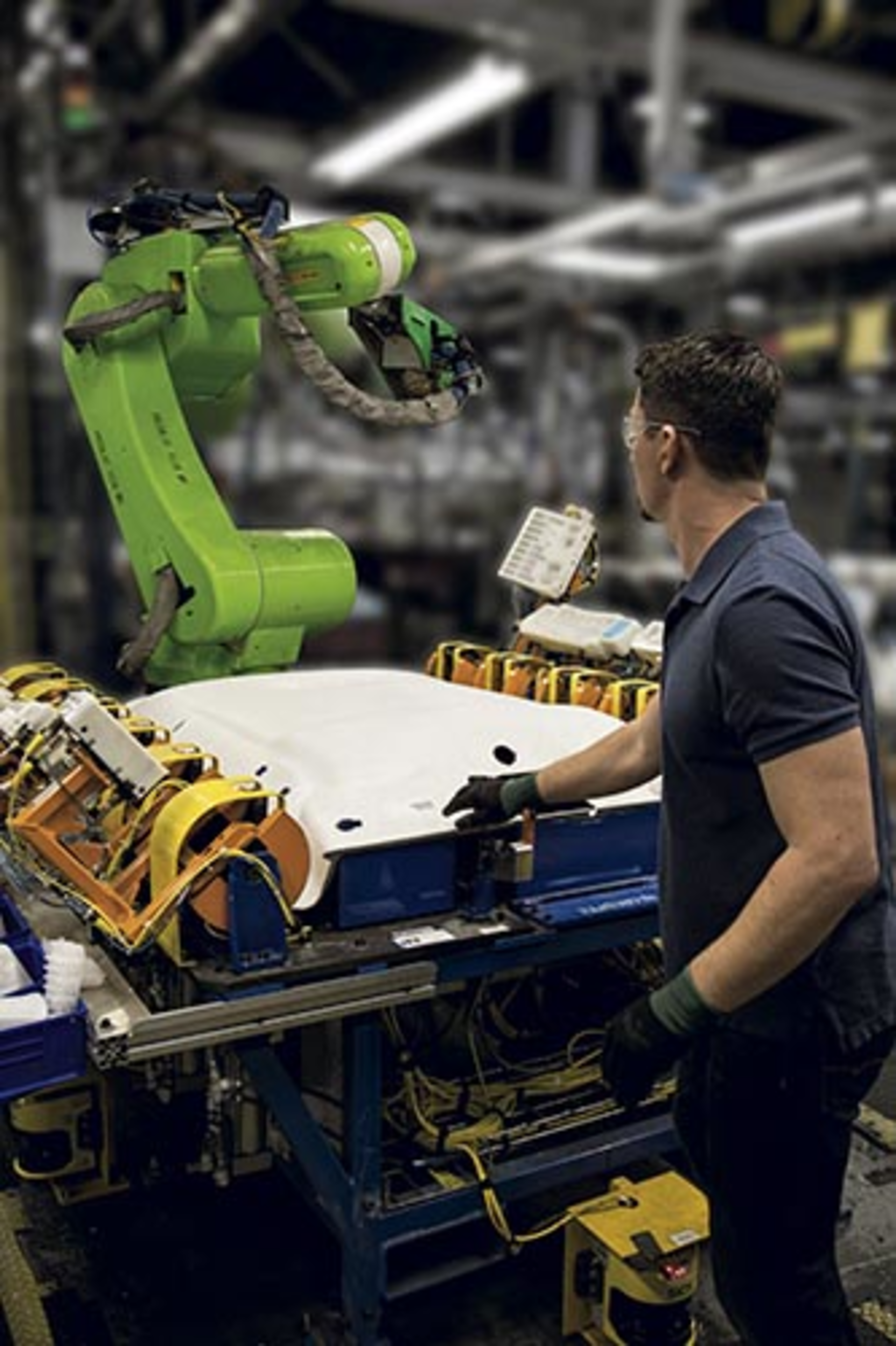 A worker reaches into a work cell that includes a Fanuc&Acirc; CR-35iA collaborative robot.