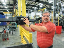 Thomson Plastics COO Rick Kibbey holds an automotive component./PMM Thomson Plastics COO Rick Kibbey holds an automotive component./PMM