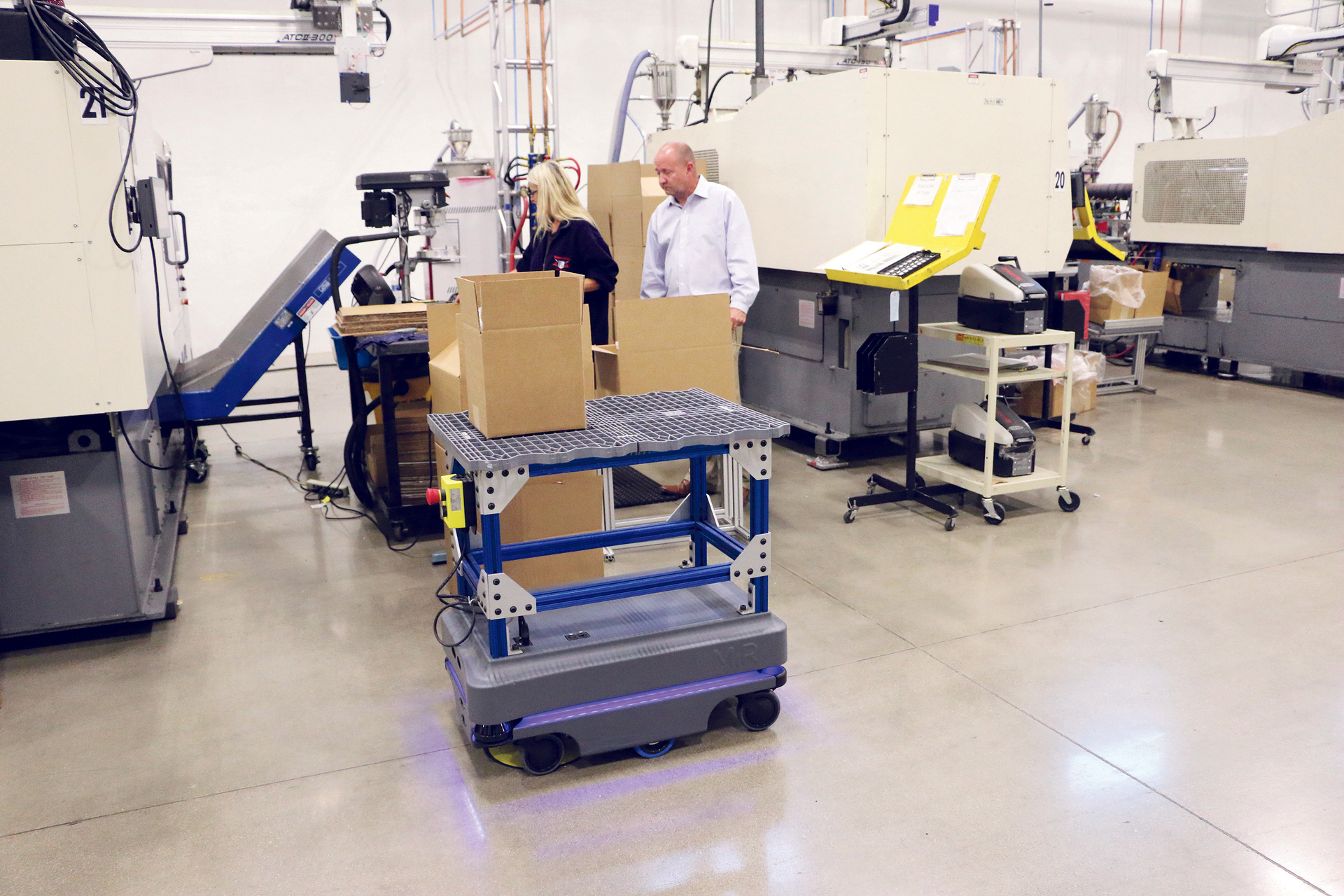 Metro Plastics President Ken Hahn examines a box of finished products delivered by the MiR200 autonomous mobile robot.