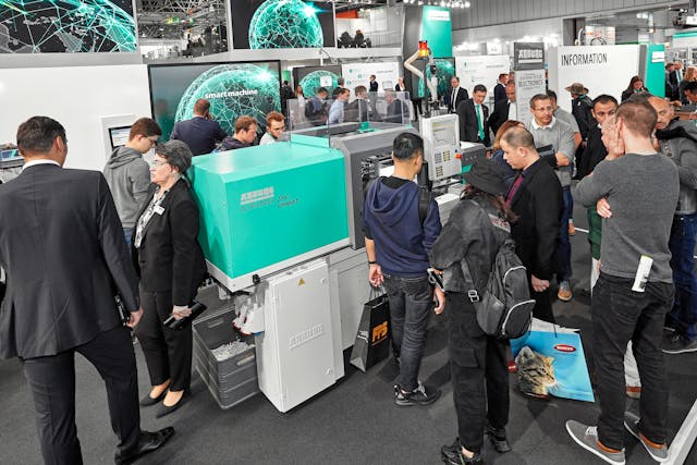 K 2019 attendees look over a new Arburg injection molding machine.