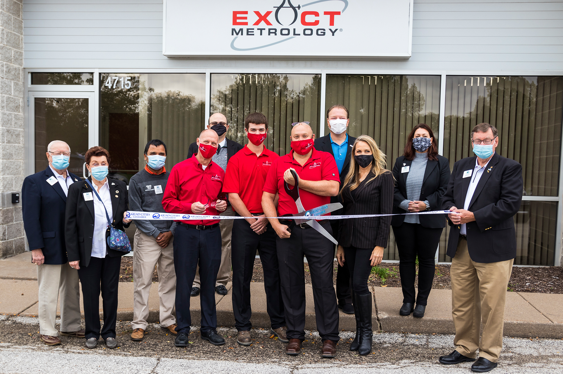 Exact Metrology personnel at the ribbon cutting ceremony in the front row were, from left to right: Dean Solberg, Patrick Wigans and Joe Wright. Members of the Quad Cities Chamber also attended.