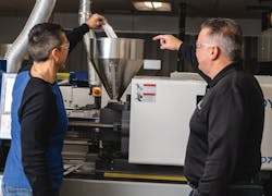 Technicians pour iD Additives' QuickShots single-dose purging compound into a machine. Technicians pour iD Additives' QuickShots single-dose purging compound into a machine.