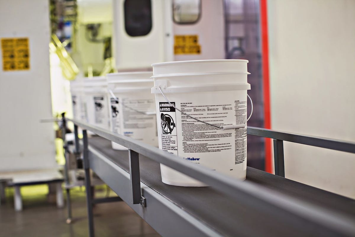 M&amp;M Industries pails travel down a conveyor belt. In a project with Engel and Top Grade Molds, M&amp;M Industries has worked to optimize the post-consumer-resin core layer in pails it makes. The new pails could hit the market soon.