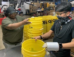 Pail maker M&amp;M Industries employees work on post-production processes. Along with Top Grade Molds and Engel, the company has been working to increase the amount of post-consumer resin it uses.