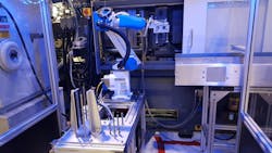 A robot from Shibaura, the company formerly known as Toshiba, operates at an injection molding machine.