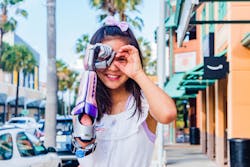 A young girl poses for a picture while using a bionic arm designed for her by Limbitless. A young girl poses for a picture while using a bionic arm designed for her by Limbitless.