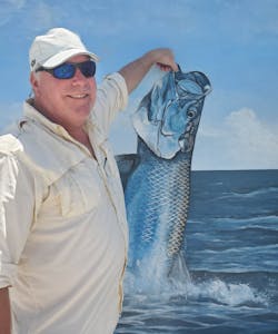 Rick Finnie strikes a creative pose in front of a painting of a fish. Rick Finnie strikes a creative pose in front of a painting of a fish.