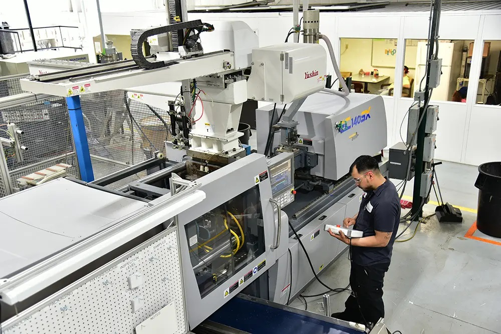 A Yushin robot is stationed above a press at Pyramid Plastics, which has been investing in new automation.