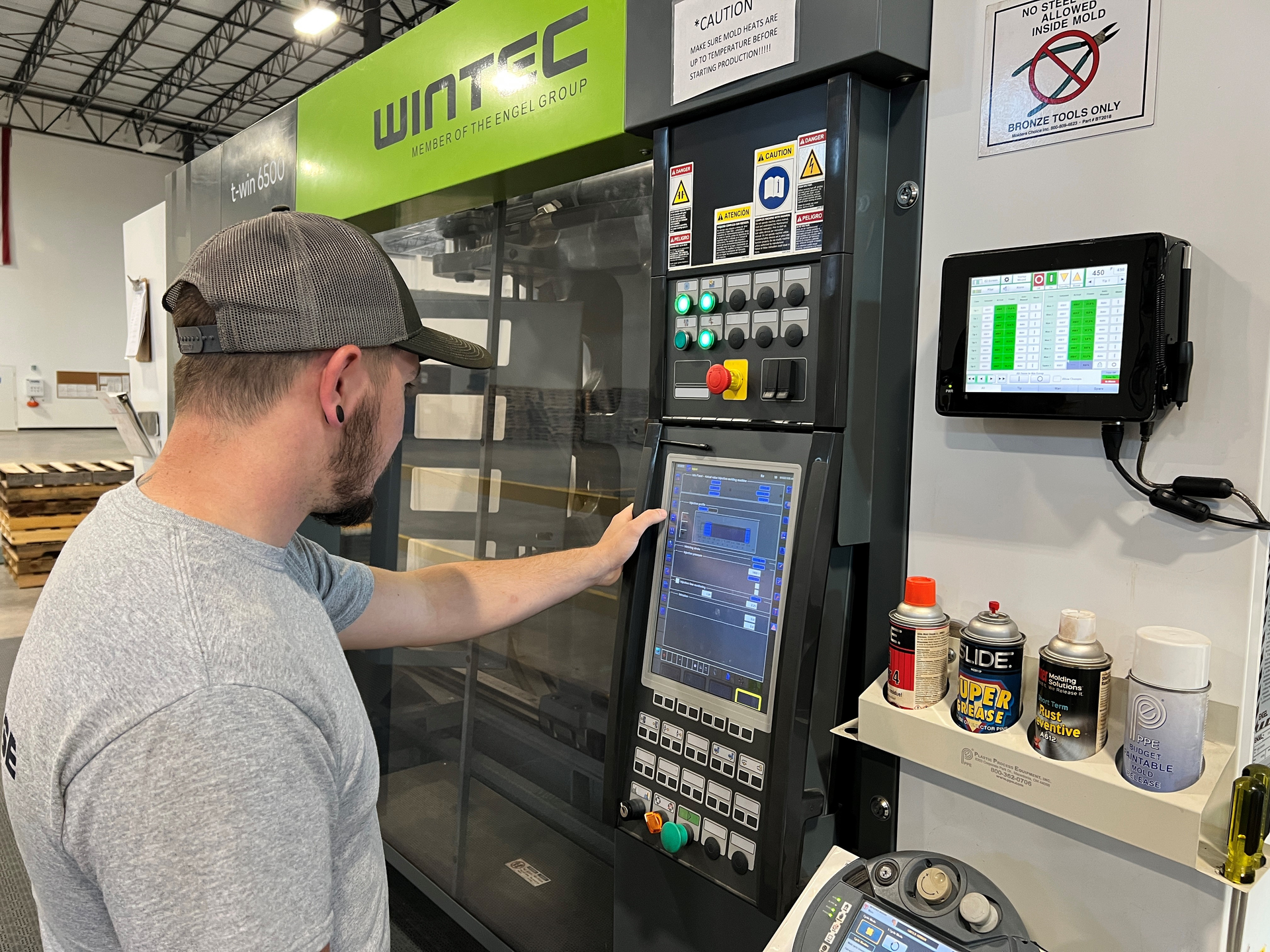 An employee works at a Wintec injection molding machine at CH3 Solutions, which makes tiles for a variety of recreational playing surfaces.