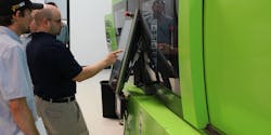 Umberto F. Catignani, president of Orbital Plastics Consulting, points out information on a touch screen as he works with a client on an injection molding machine.