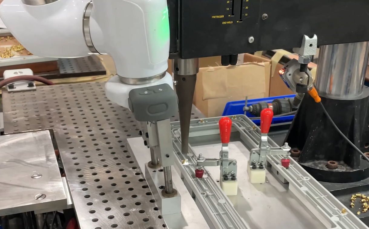 At Ferriot Inc., a tray fabricated by the company's automation department holds a plastic part, and is guided under an ultrasonic welder by a cobot. After each metal insert is joined to the part by the welder, the cobot repositions the tray for the next weld to be made.