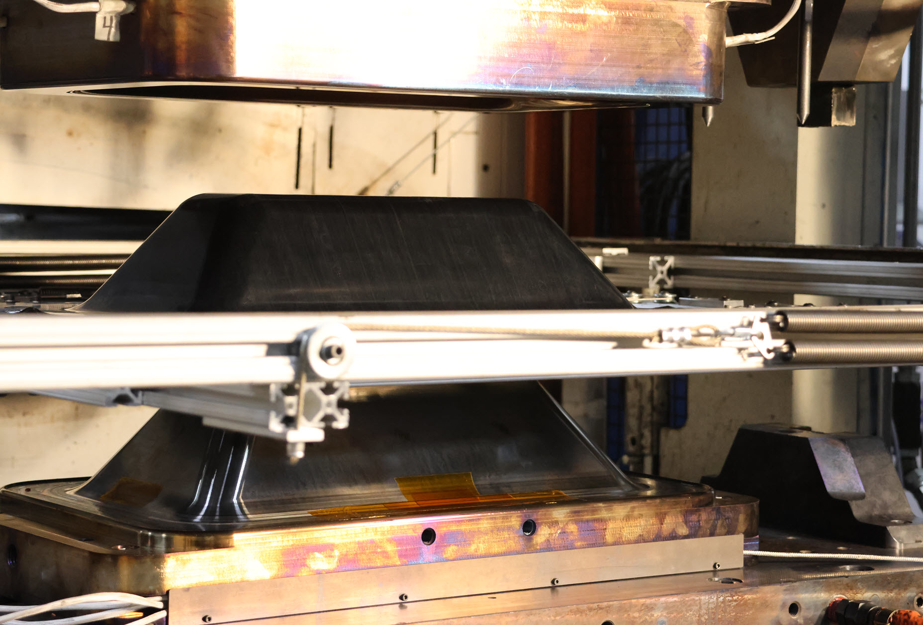 Tri-Mack stamp forms thermoplastic composite enclosures in minutes using tooling designed and made in-house. The enclosure shown is mounted on a shuttle after stamp-forming in mold.