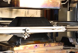 Tri-Mack stamp forms thermoplastic composite enclosures in minutes using tooling designed and made in-house. The enclosure shown is mounted on a shuttle after stamp-forming in mold. Tri-Mack stamp forms thermoplastic composite enclosures in minutes using tooling designed and made in-house. The enclosure shown is mounted on a shuttle after stamp-forming in mold.