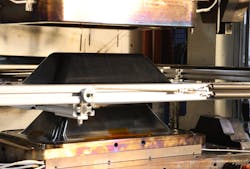 Tri-Mack stamp forms thermoplastic composite enclosures in minutes using tooling designed and made in-house. The enclosure shown is mounted on a shuttle after stamp-forming in mold. Tri-Mack stamp forms thermoplastic composite enclosures in minutes using tooling designed and made in-house. The enclosure shown is mounted on a shuttle after stamp-forming in mold.