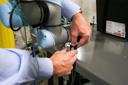 The FlexxReference add-on from Flexxbotics allows non-robot programmers to more easily set up cobot waypoints along their path of motion. Here, a user adjusts the feature's locking mechanism on a UR5e cobot at Aim Processing. The FlexxReference add-on from Flexxbotics allows non-robot programmers to more easily set up cobot waypoints along their path of motion. Here, a user adjusts the feature's locking mechanism on a UR5e cobot at Aim Processing.