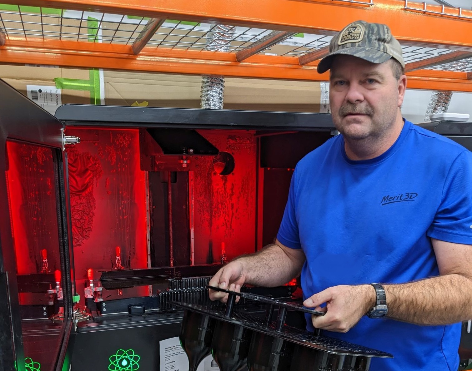 Justin Slaughter removes parts made by 3D printers at Merit3D.