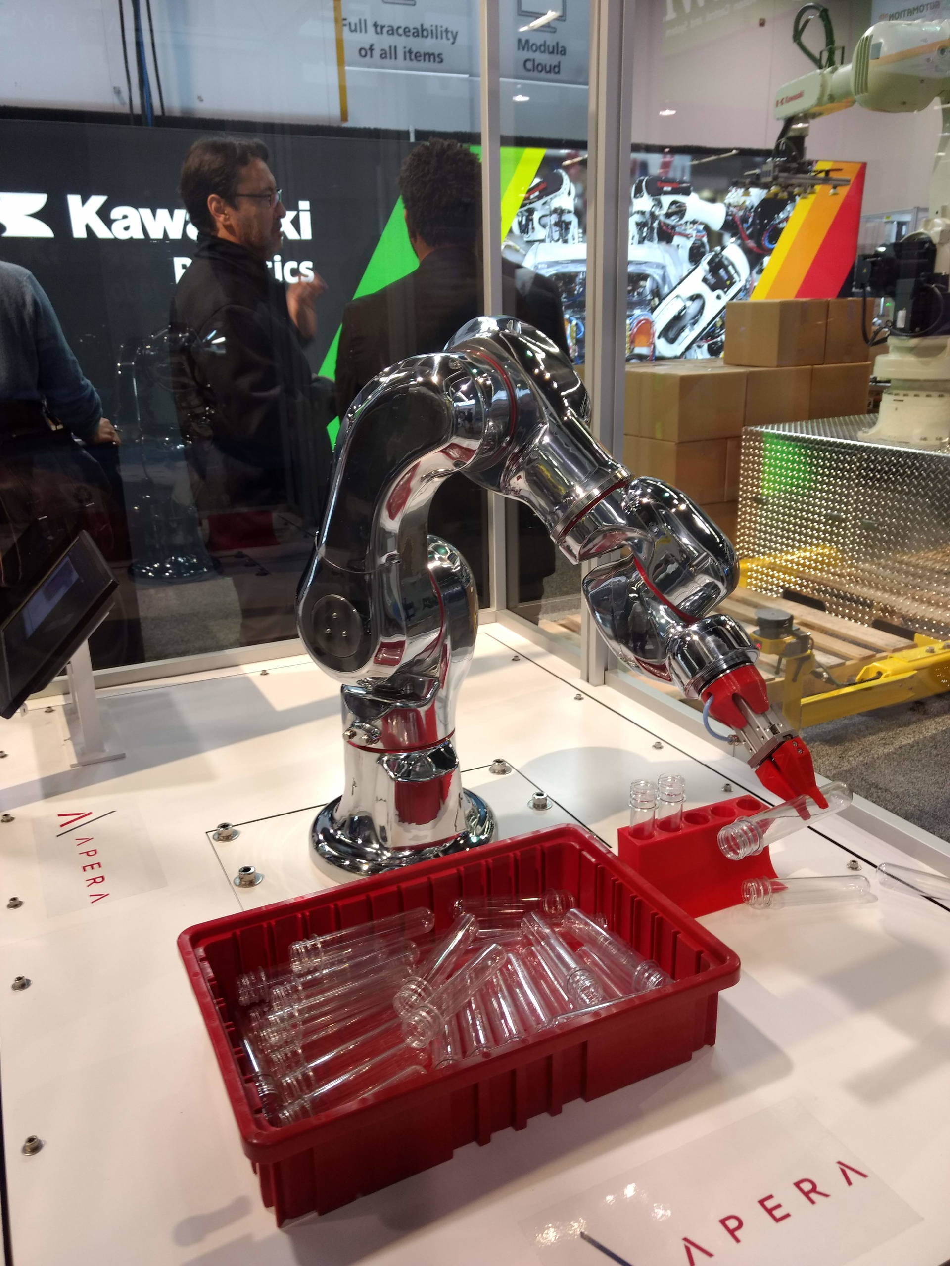 A Kawasaki MC-series robot uses an Apera AI vision system to take plastic test tubes from a bin and place them in a fixture.