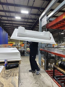 A Duo Form worker removes a train interior panel from the press for trimming.