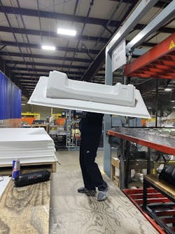 A Duo Form worker removes a train interior panel from the press for trimming. A Duo Form worker removes a train interior panel from the press for trimming.
