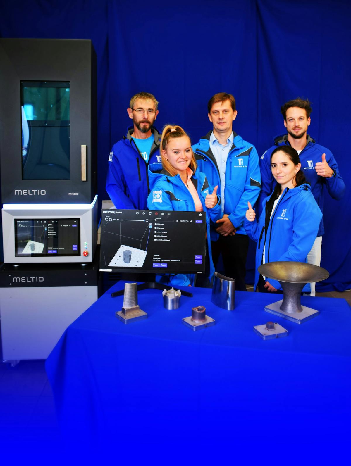 Meltio, the Linares, Spain-based manufacturer of wirelaser metal deposition 3D printers, announced it has named B&uuml;ttner Ltd. its first official sales partner in Hungary. The B&uuml;ttner additive manufacturing team in Hungary stands with samples of parts created by a Meltio printer.