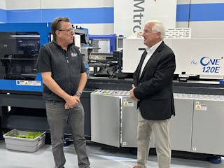 Peter Gardner (left), president of LS IMM USA, and Paul Caprio, president of sales, are shown with an injection molding machine in the Wood Dale, Ill., technical center.