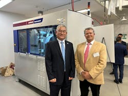 WITTMANN USA President David Preusse, right, and Ho-Seon Jin, Eli Lilly senior director-engineering, stand in front of the Wittmann MicroPower injection molding machine that was part of the work cell donated to the University of Massachusetts Lowell.