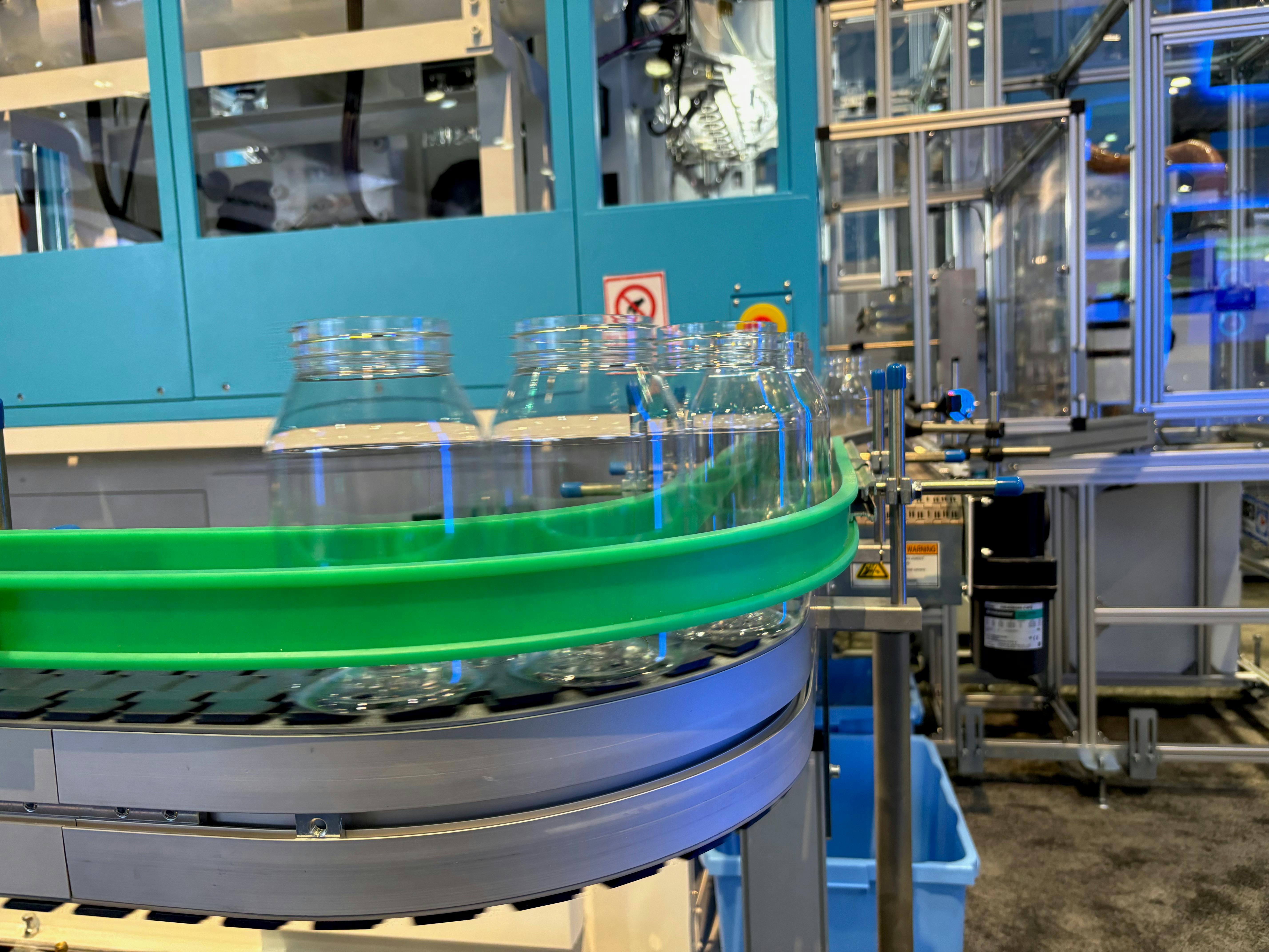 Blow molded jars whiz by on a line at NPE2024.