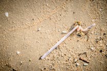 A discarded plastic straw on a beach. A discarded plastic straw on a beach.