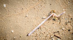A discarded plastic straw on a beach. A discarded plastic straw on a beach.