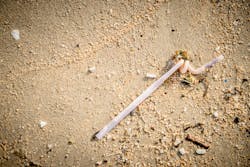 A discarded plastic straw on a beach. A discarded plastic straw on a beach.
