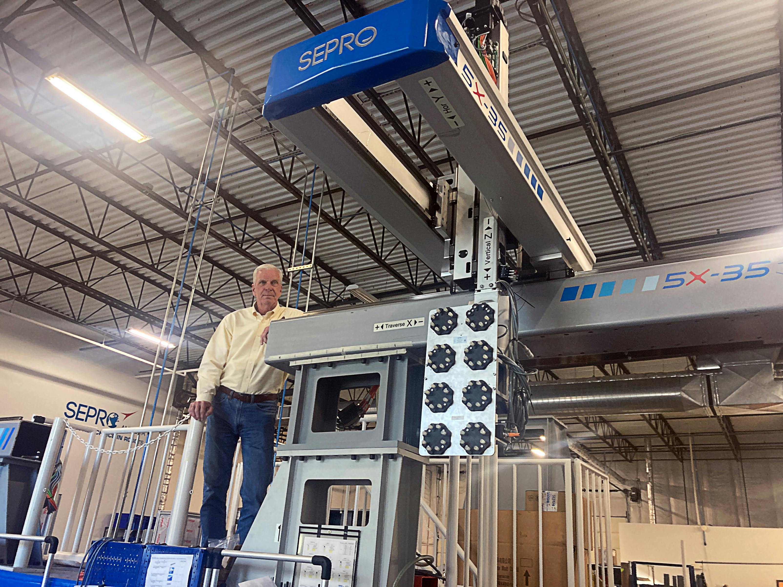 Jim Healy, VP of sales and marketing for Sepro America, poses alongside a large robot.