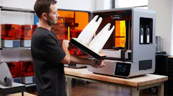 A person removes a part from a Formlabs Form 4L printer.