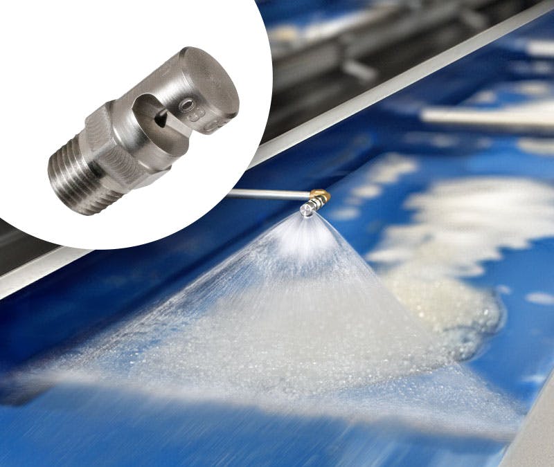 An Exair FloodStream nozzle sprays suds onto a blue surface.