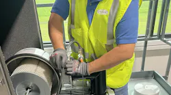 As part of a SureLaunch visit, a Conair technician inspects and validates the installation of a large central vacuum pump prior to successful commissioning and startup of a conveying system.