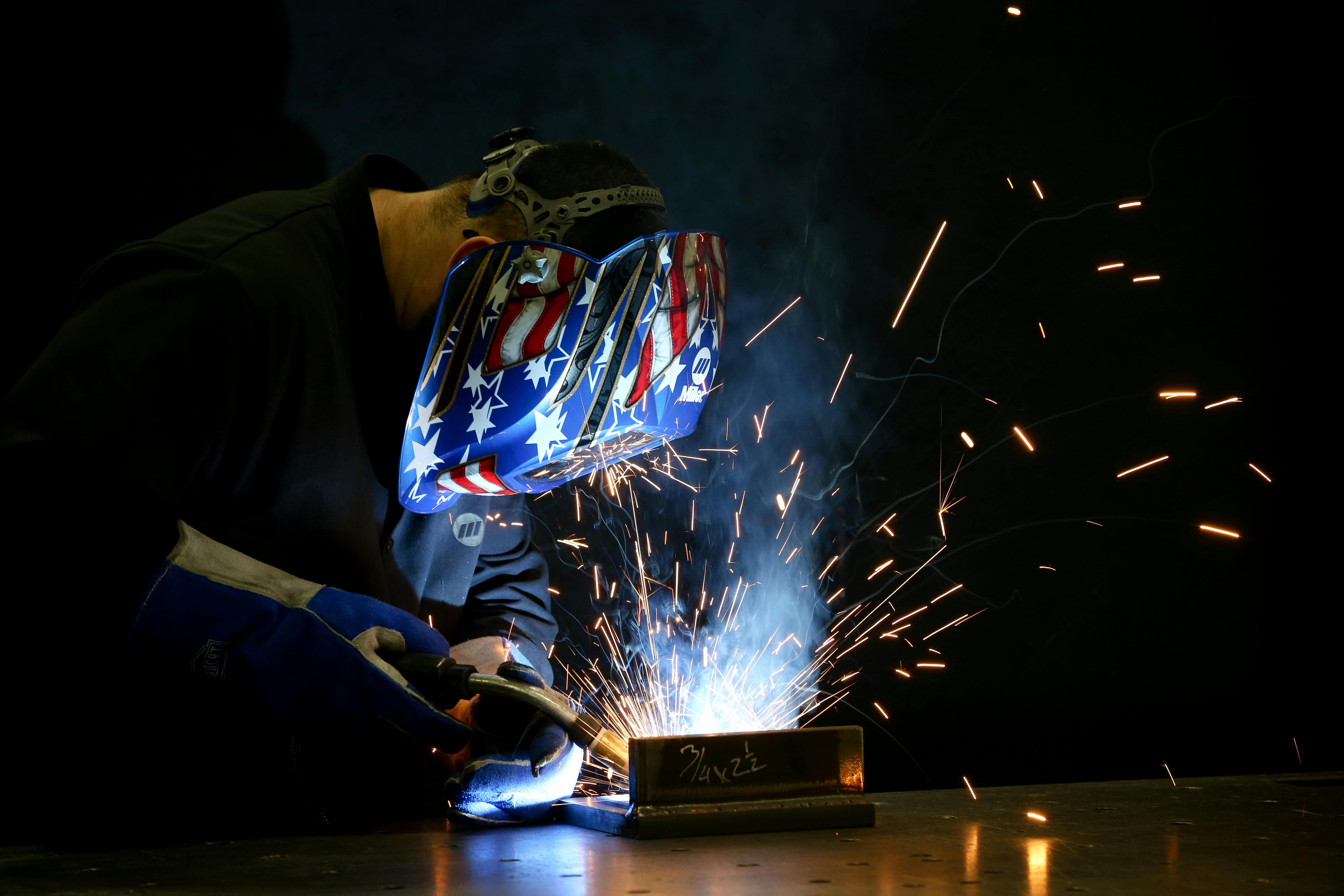 A worker welds a part for a new blow molding machine at Bekum America.