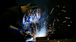 A worker welds a part for a new blow molding machine at Bekum America.