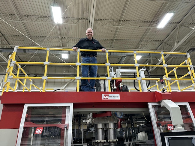 R&B Plastics Machinery President and GM Fred Piercy atop a blow molding machine at the company's Saline. Mich., plant.
